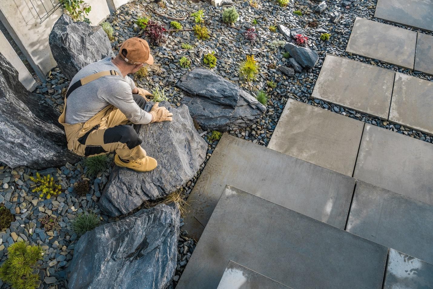 Skilled landscape designer arranging gravel in a modern backyard for a contemporary outdoor space.